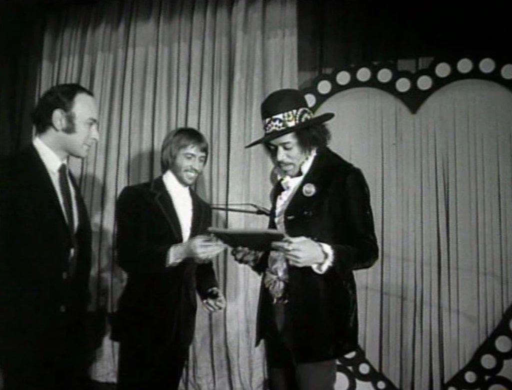 Jimi Hendrix holding an award, presented by Maurice Gibb in 1969 for being named the top musician in the world.