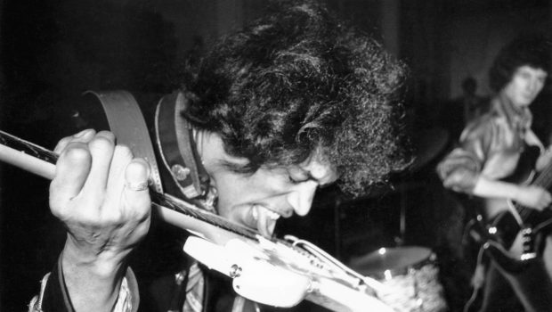 Jimi Hendrix on stage in 1967 in the UK, playing his guitar using his tongue.