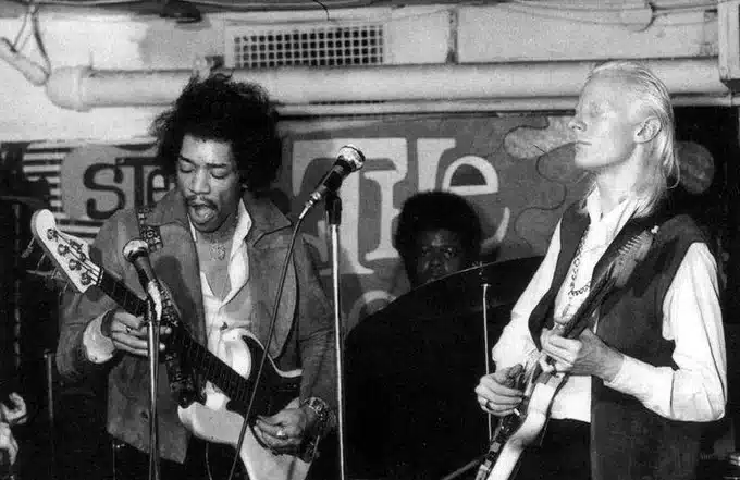 A photograph showcasing Jimi Hendrix playing the bass, Johnny Winter on guitar, and Buddy Miles on drums, immersed in a powerful musical moment.