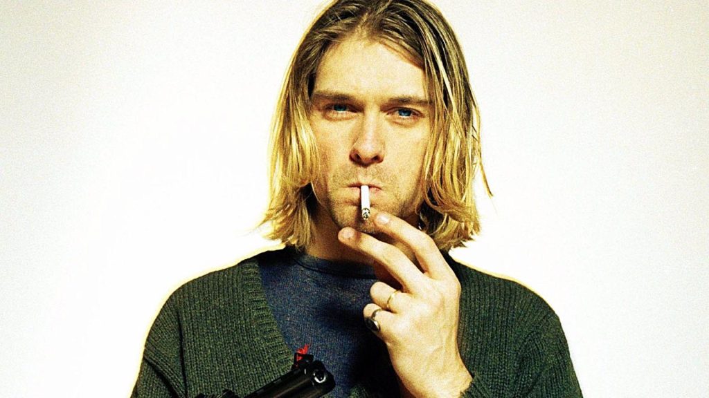 Kurt Cobain Wallpaper smoking a cigar with a gun in his hand.