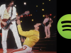 10 Most Popular Rock Bands In 2025 (Spotify Monthly Listeners) Freddie Mercury kneeling in front of the guitarist on stage next to the green Spotify logo, illustrating the most popular rock bands on Spotify in 2025.